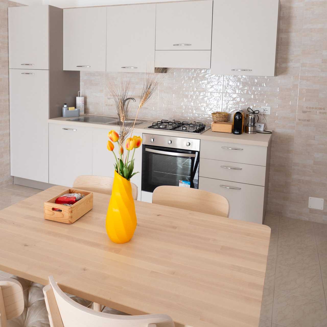 Tavolo della cucina con un vaso giallo stampato in 3D e dei tulipani